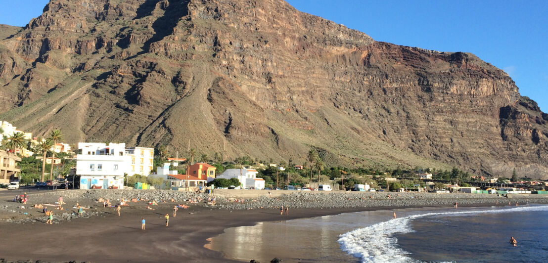 Dunkler Sandstrand auf La Gomera vor einem großen Berg.