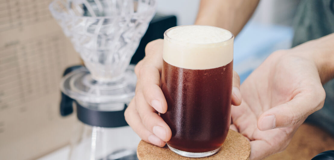 Beschnittene Aufnahme von Barista, der ein kaltes Getränk serviert