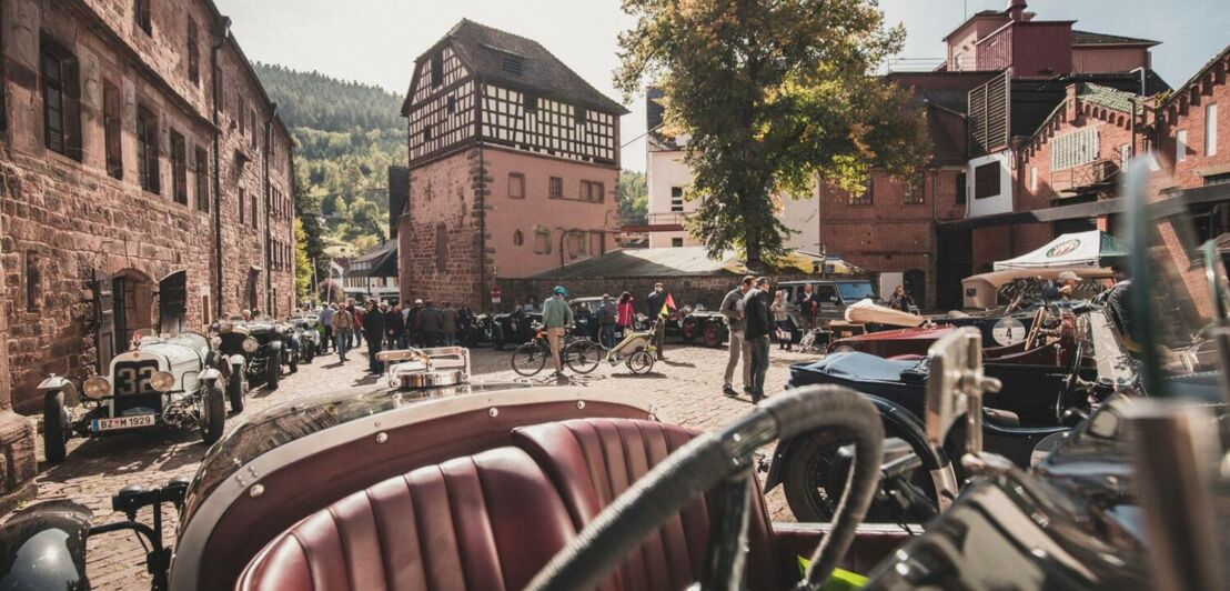 Parkende Oldtimer und Menschen auf einem Burghof