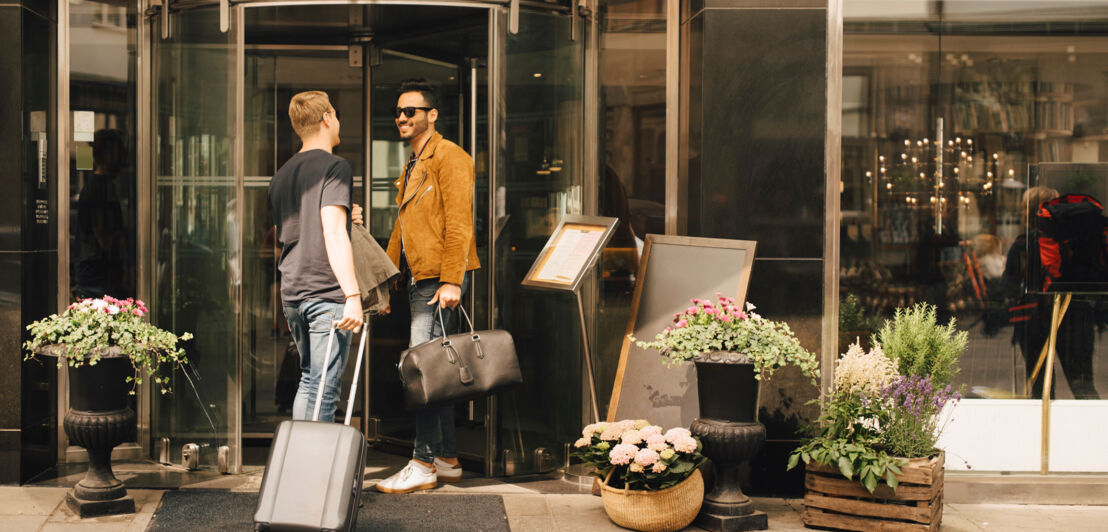 Zwei junge Männer unterhalten sich vor der Tür eines Hotels