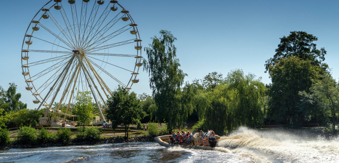 Ein Motorboot auf einem See, im Hintergrund ein Riesenrad