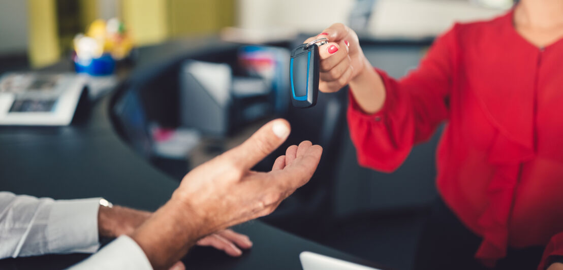 Übergabe eines Autoschlüssels am Schalter