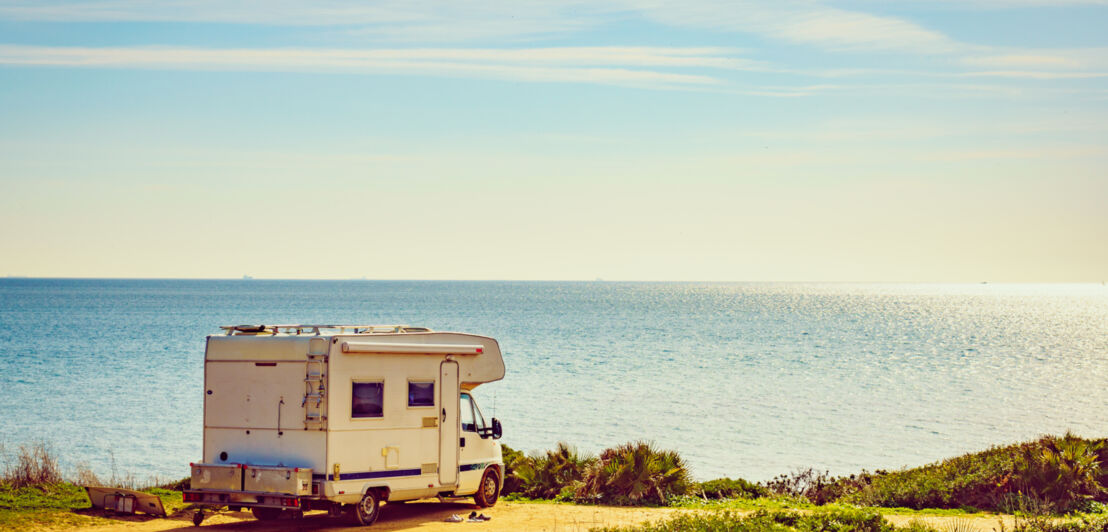 Ein Wohnmobil, das auf einer Klippe steht, dahinter das Meer