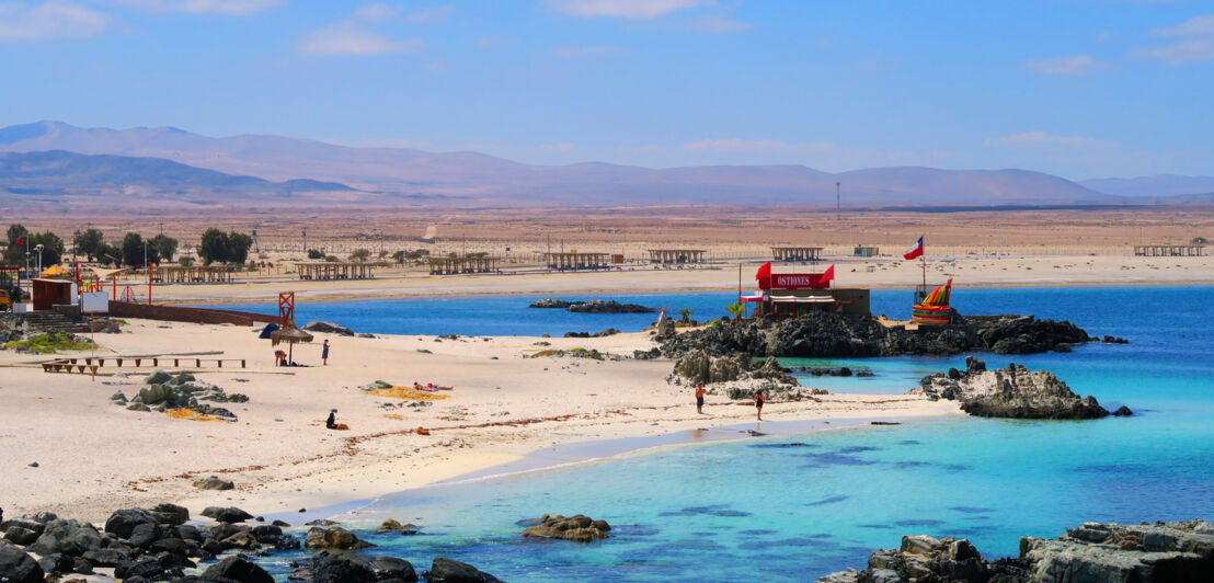 Eine Bucht in einem Urlaubsort mit Sandstrand und flachen Felsformationen