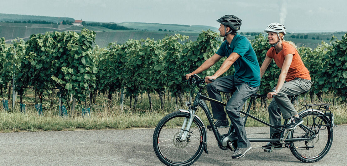 Ein Paar auf einem Tandem an einem Weinberg