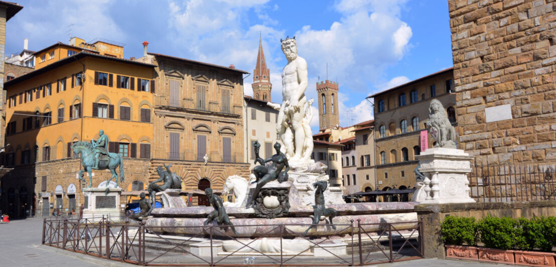 Ein Brunnen mit mythologischen Statuen am Rande eines Platzes