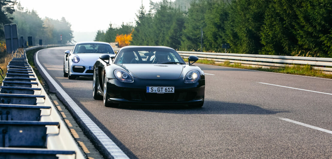 Ein Porsche 911 Turbo S und ein Carrera GT auf einer Rennstrecke.