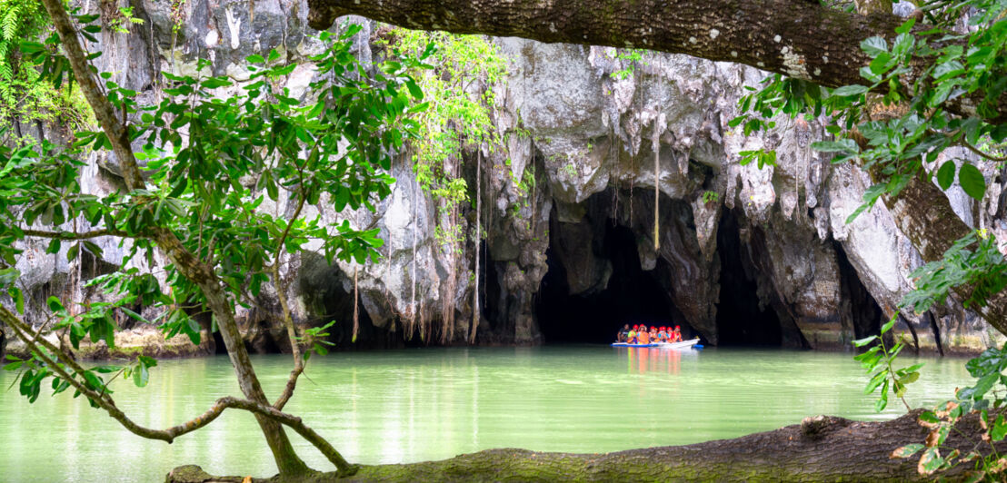 Ein Ausflugsboot fährt auf dem Wasser in eine Felsgrotte hinein