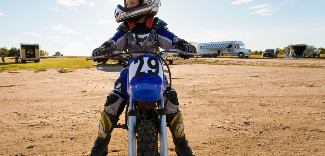 Junge sitzt auf Motocross-Motorrad.