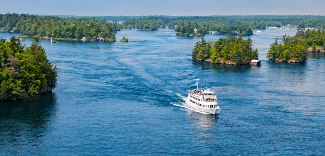 Ein Schiff fährt im kanadischen Nationalpark Thousand Islands an vielen kleinen Inseln vorbei.