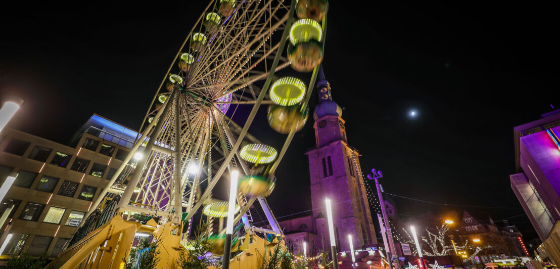 Blick aus der Froschperspektive auf ein Riesenrad bei Nacht