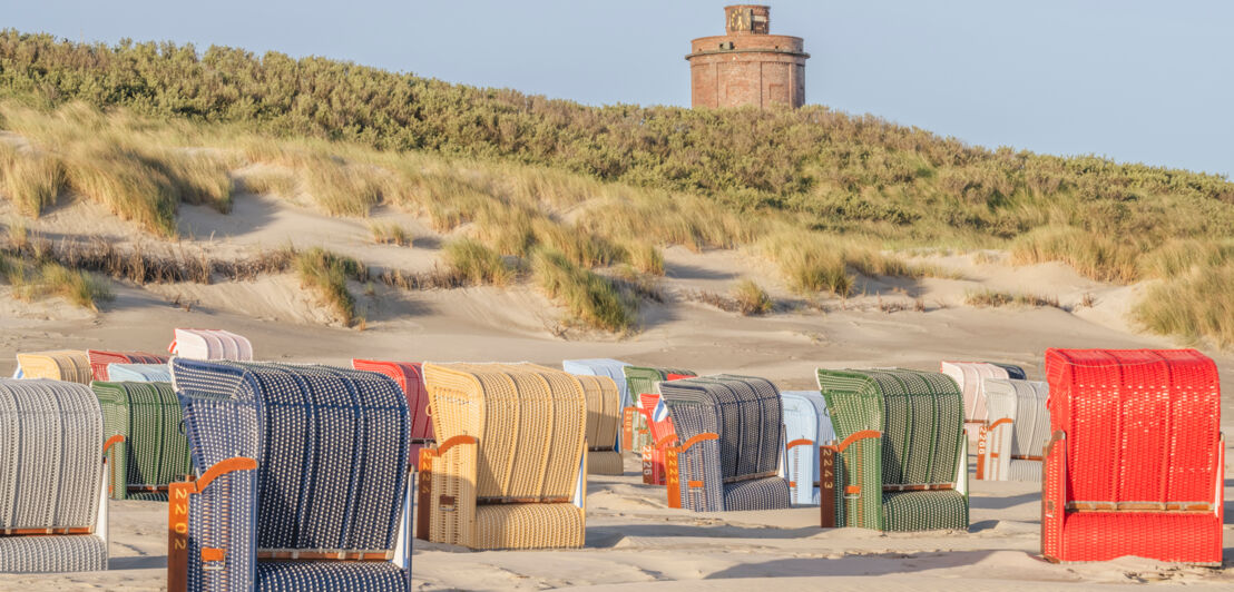 Strandkörbe am Strand vor der Düne mit dem Wasserturm von Juist