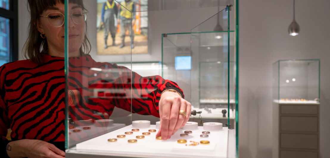 Beraterin legt im Atelier von Jan Spille Ringe in eine Vitrine