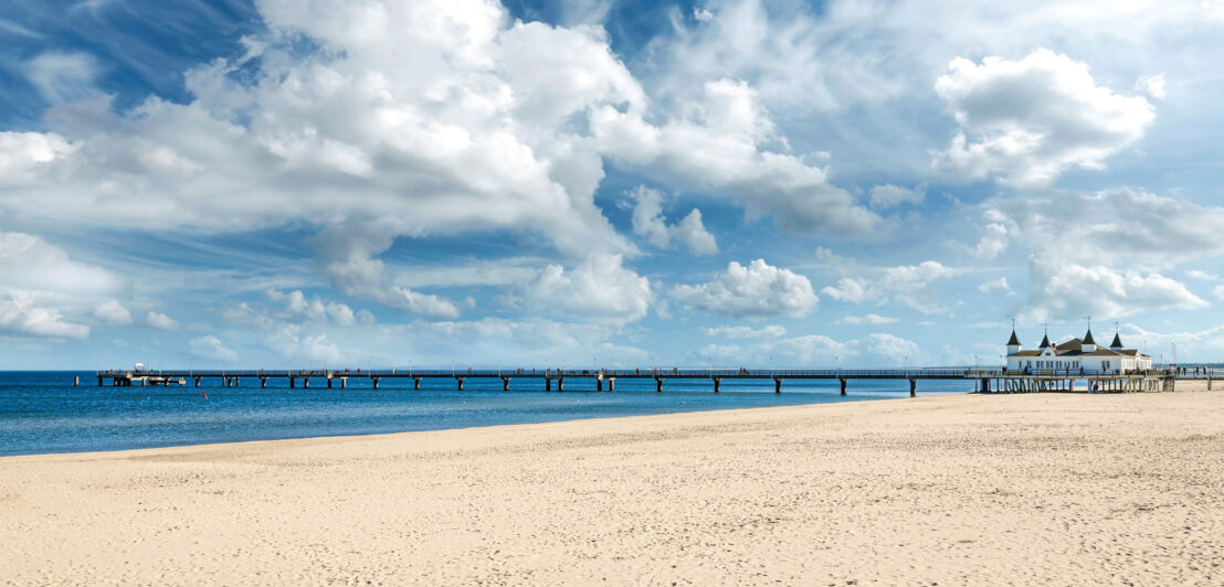 Menschenleerer, breiter Sandstrand mit Pier