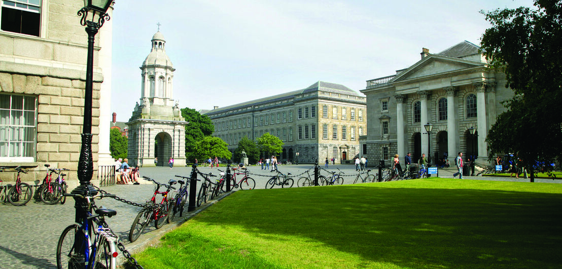 Das Trinity College mit einer Grünanlage im Vordergrund und mehreren abgestellten Fahrrädern