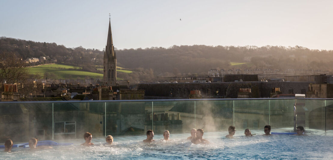 Badende in einem Rooftop-Pool mit Blick auf das historische Bath