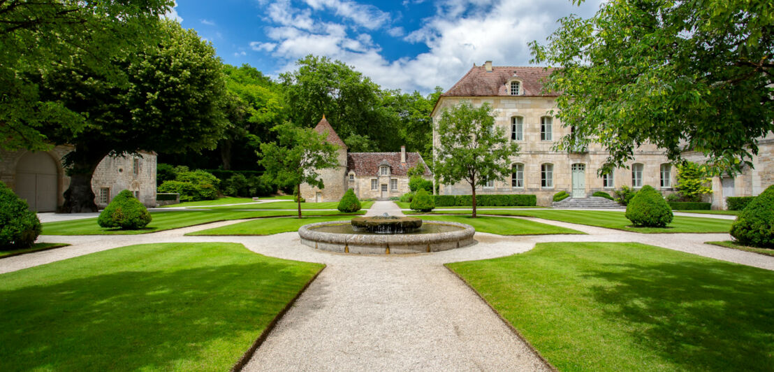 Landschaftsgarten mit Rasenflächen, Wegen und Springbrunnen innerhalb einer Klosteranlage