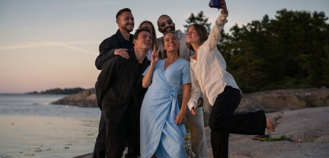 Eine junge Clique am Strand macht ein Selfie