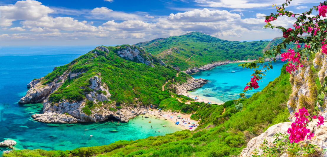 Blick auf den Timoni Beach mit türkisem Wasser und bewachsenen Bergen