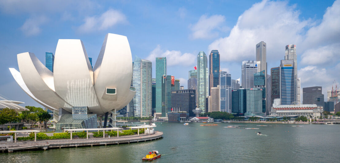 Skyline von Singapur an der Marina Bay mit einem weißen, modernen Museumsgebäude in Lotusblütenform im Vordergrund