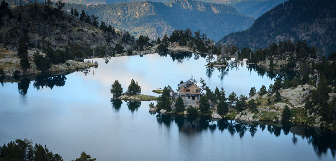 Idyllische Berglandschaft mit See, an dem eine einzelne Hütte steht