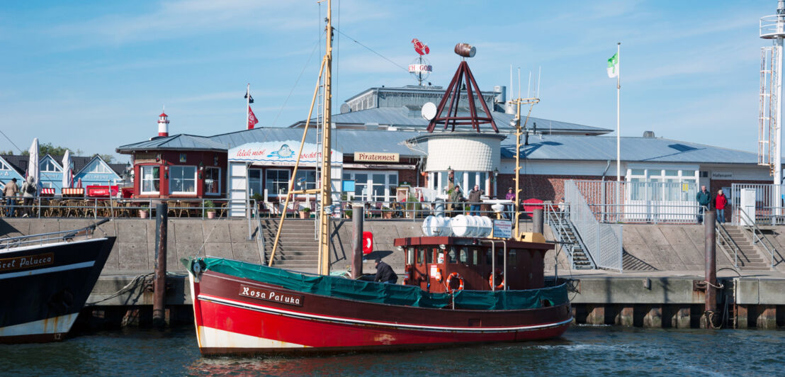 Ein Ausflugsboot an einer Hafenpromenade mit Geschäften