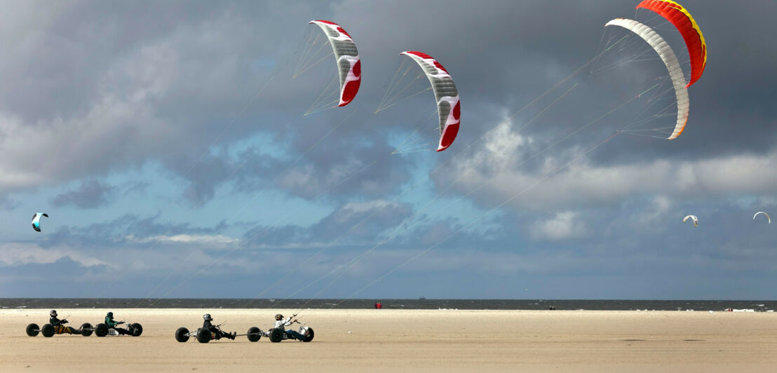 Kitebuggys am Strand von St. Peter Ording vor bewölktem Himmel