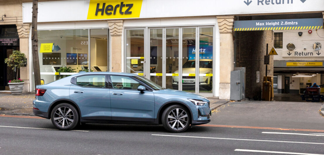 Ein Auto steht vor einer innerstädtischen Filiale des Mietwagenunternehmens Hertz.