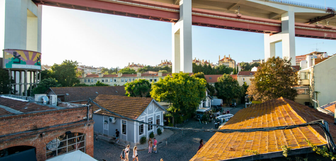 Belebtes Industrieviertel mit Geschäften am Fuße einer Brücke.