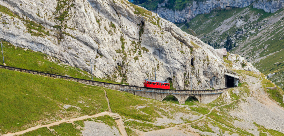 Eine rote Zahnradbahn in karger Berglandschaft.