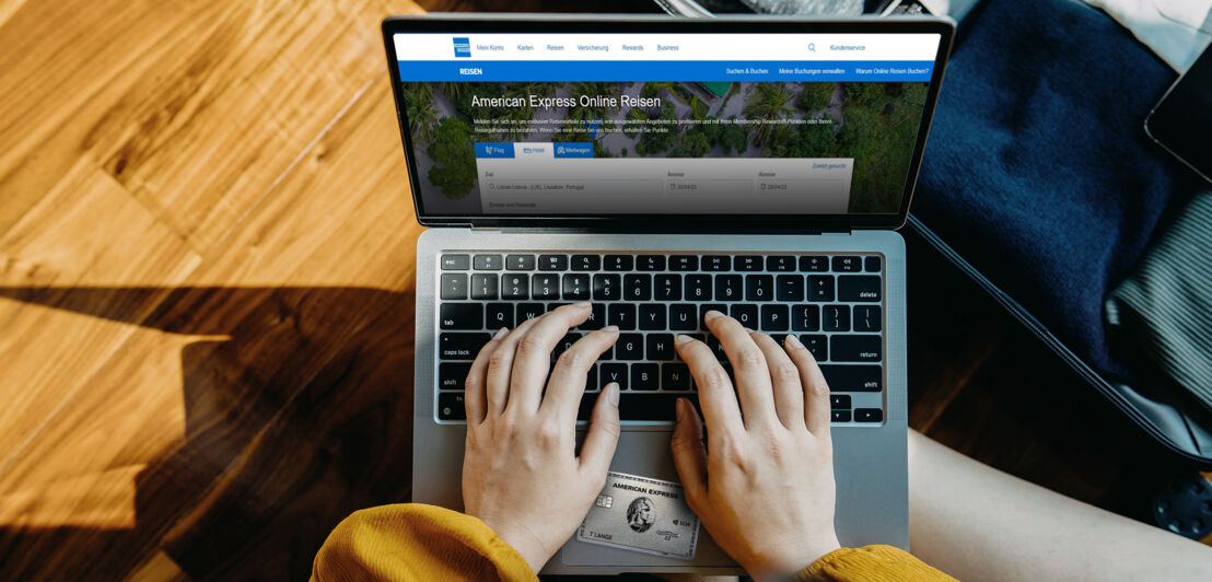 Aufsicht zweier Hände an einem Laptop bei der Buchung einer Reise über den American Express Online-Reiseservice mit einer Platinum Card.