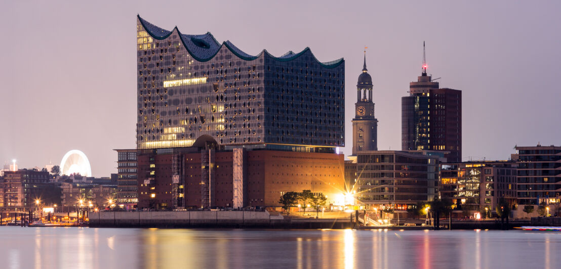 Elbphilharmonie und Kirchturm des Michels in Hamburg bei Dunkelheit.