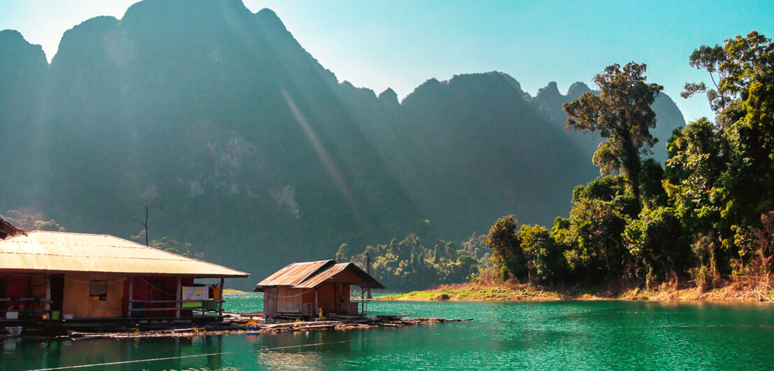 Floßhäuser schwimmen auf dem Cheo-Lan-See, im Hintergrund Berge. Khao Sok Nationalpark, Khao Lak.