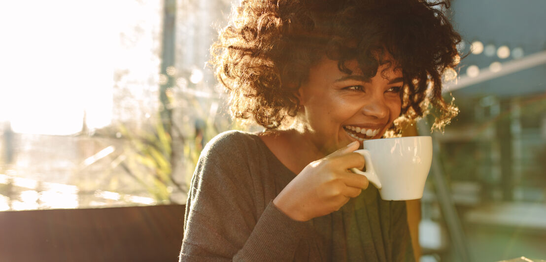 Eine junge Frau genießt eine Tasse Kaffee im freien