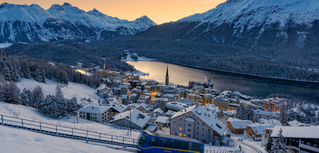 Panorama von St. Moritz am See vor Bergpanorama bei Abenddämmerung.