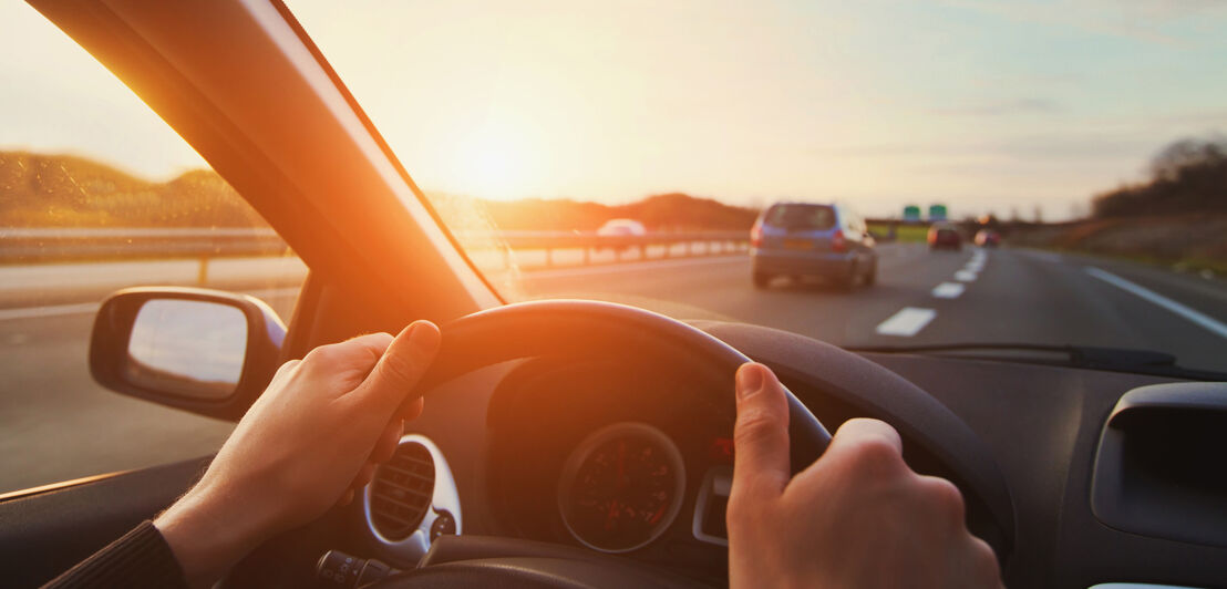 Hände am Lenkrad während einer Fahrt auf der Autobahn