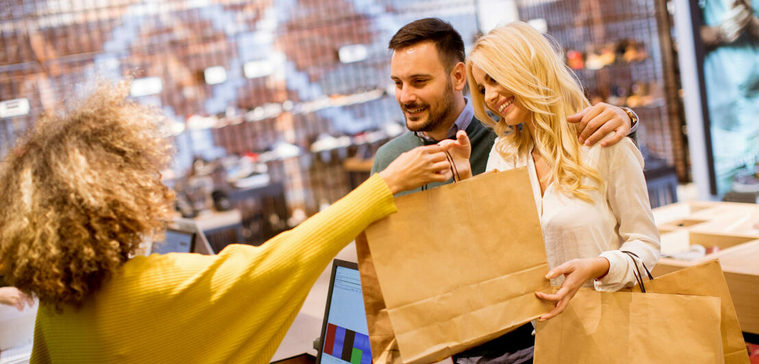 Glückliches Paar bezahlt in einer Boutique