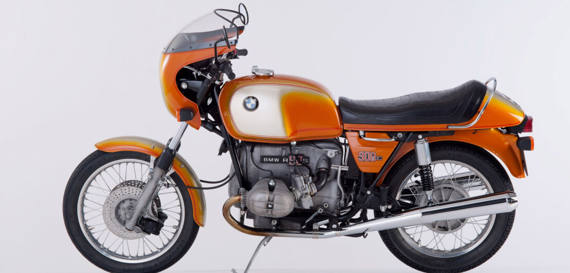 Orangefarbenes Motorrad R 90 S von BMW, Studioaufnahme vor weißem Hintergrund.