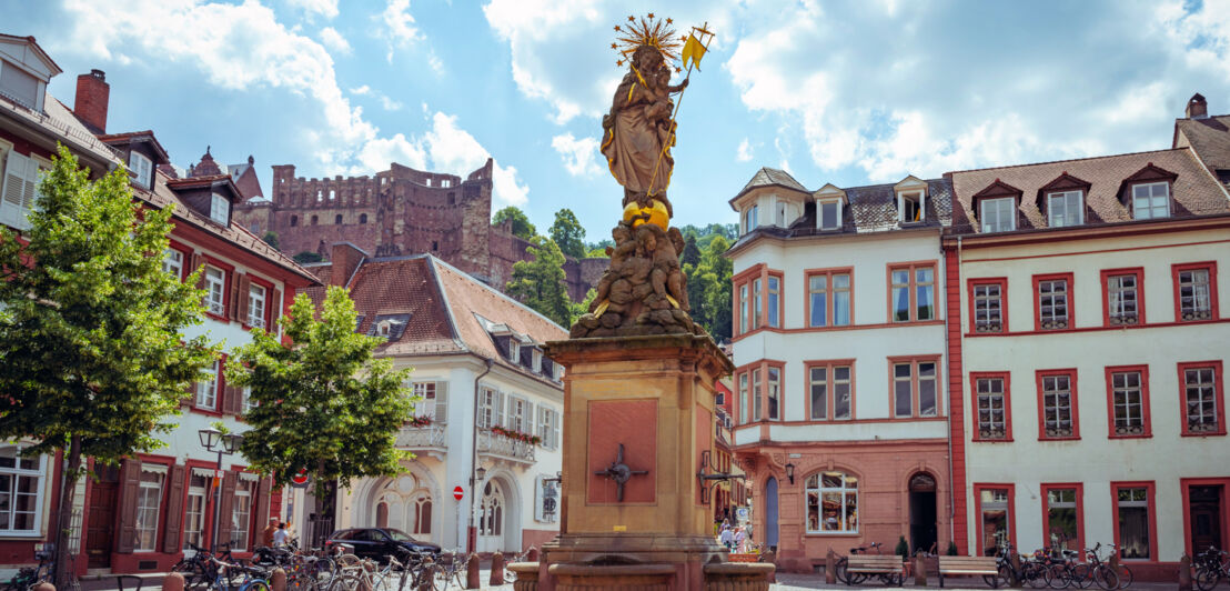 Platz mit Brunnen vor farbenfrohen Häusern in der Altstadt von Heidelberg.