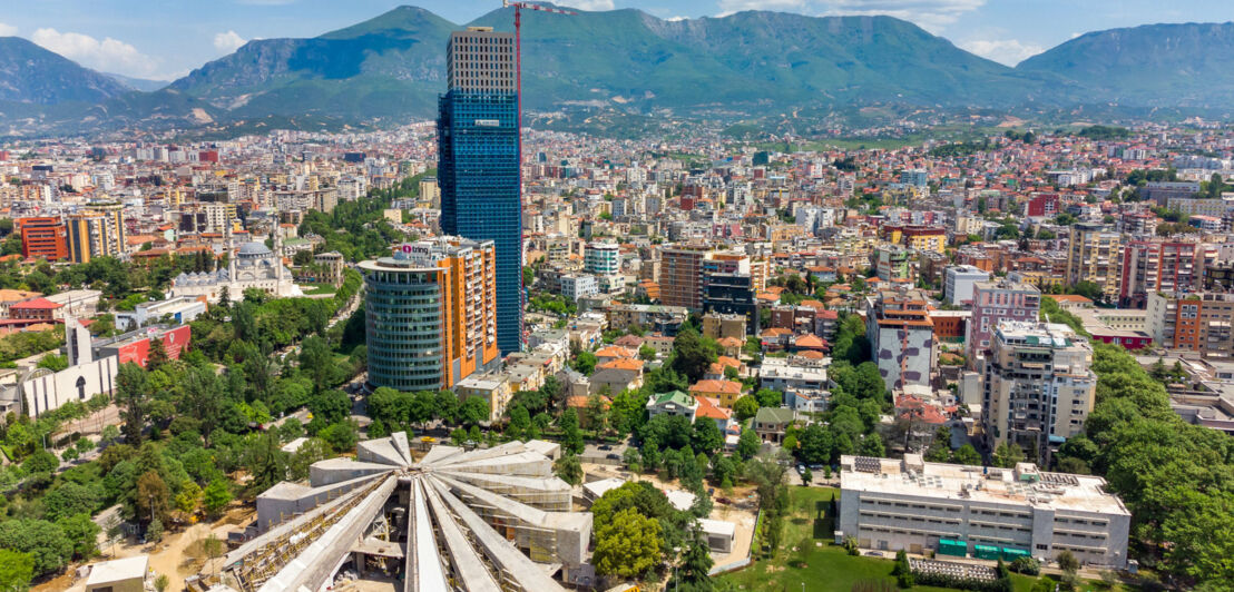 Luftaufnahme der albanischen Hauptstadt Tirana mit Bergen im Hintergrund.