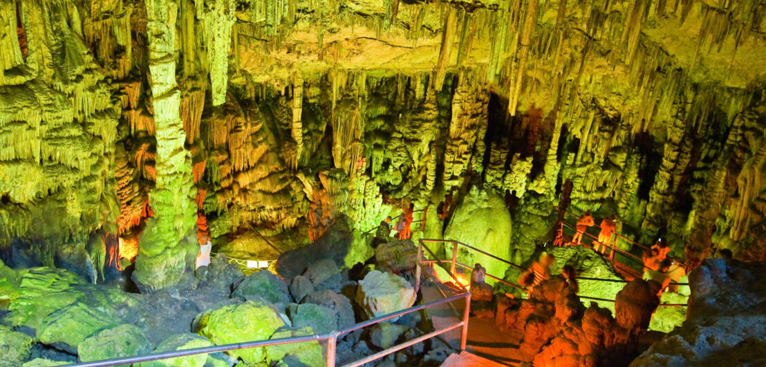 Personen in einer grün beleuchteten Tropfsteinhöhle.