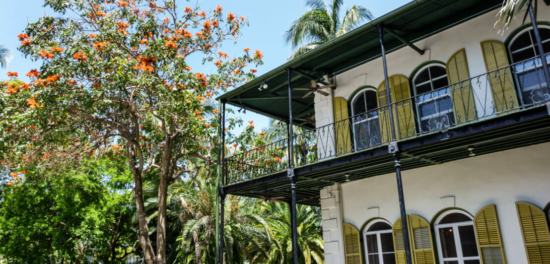 Historisches Haus im spanischen Kolonialstil, umgeben von einem Garten mit subtropischer Vegetation.