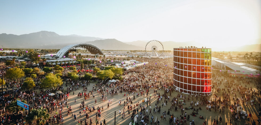 Luftaufnahme über das Gelände des Coachella Festivals mit vielen Personen, einer Bühne und einem Riesenrad.