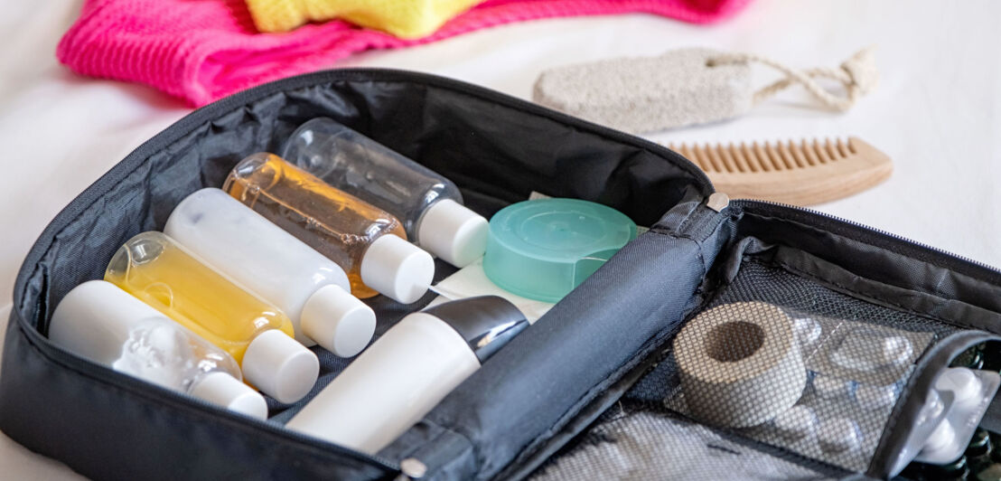 Nahaufnahme einer Kosmetiktasche mit gefüllten Plastikflaschen im Reiseformat. Nahaufnahme einer Kosmetiktasche mit gefüllten Plastikflaschen im Reiseformat.