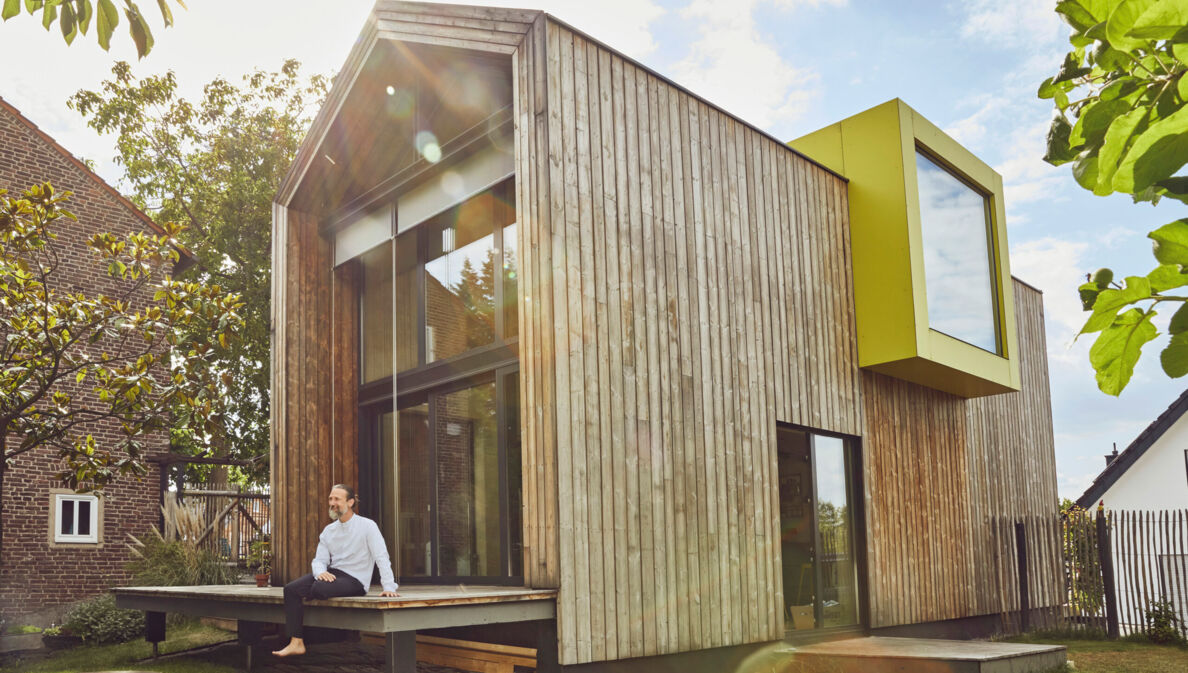 Ein Mann sitzt auf der Terrasse eines Tiny Houses