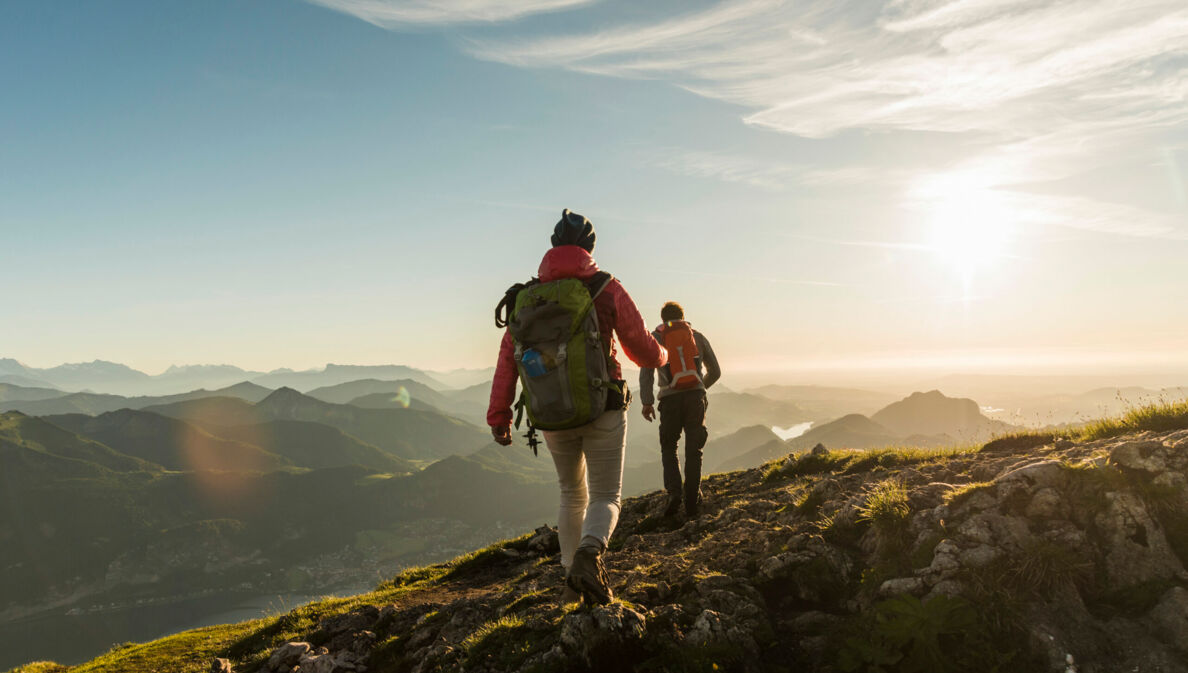 Zwei Personen wandern auf einem Berg mit beeindruckendem Panorama.