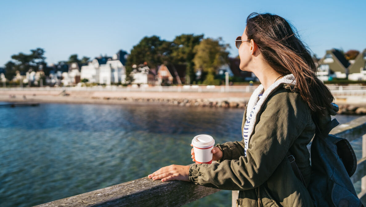 Eine junge Frau steht auf einer Seebrücke