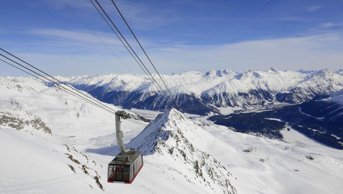 Eine Seilbahn fährt über ein bergiges Skigebiet bei St. Moritz.