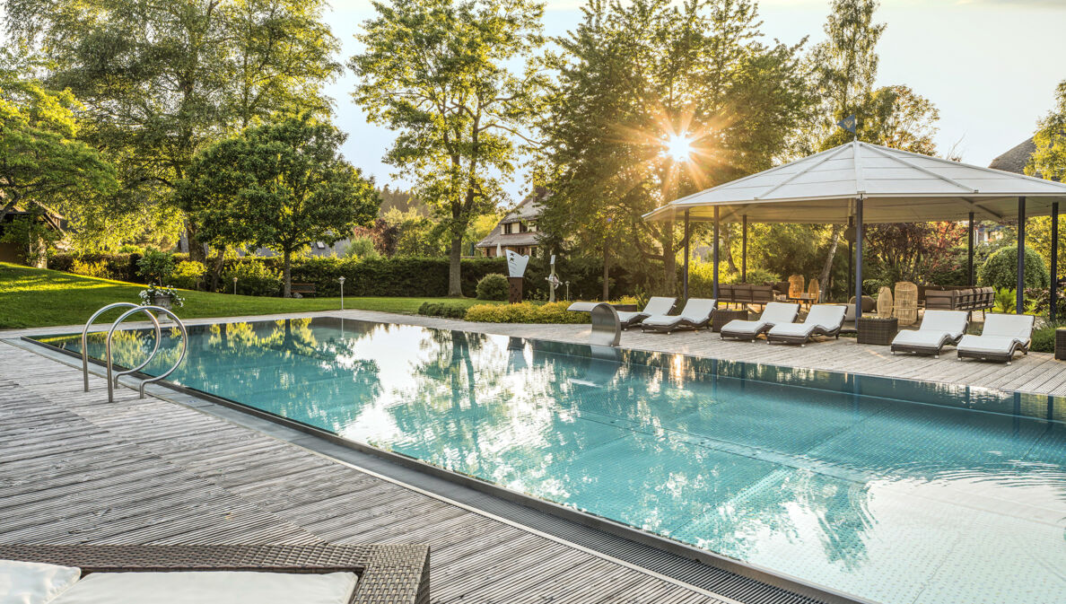 Elegante Terrasse mit Außenpool und Liegestühlen in begrünter Umgebung