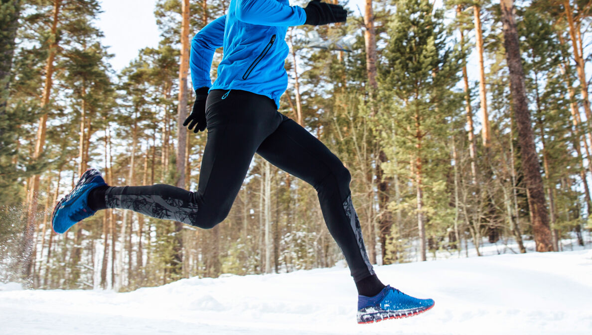 Ein Mann joggt im verschneiten Wald.